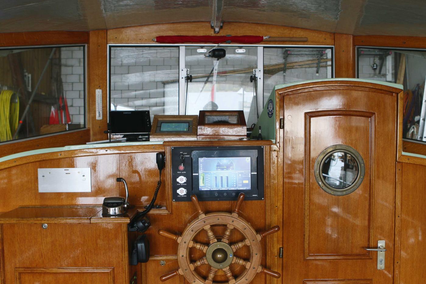 Poste de pilotage avec câble de recharge branché et écran affichant diverses informations au-dessus du gouvernail.