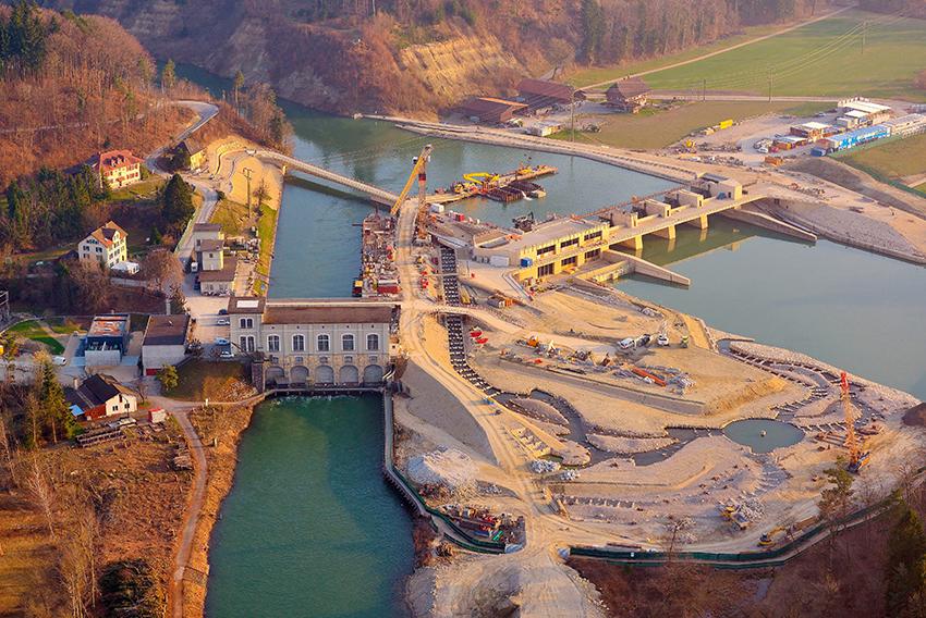 Bau des neuen Wasserkraftwerks mit markantem Fischumgehungsgerinne.