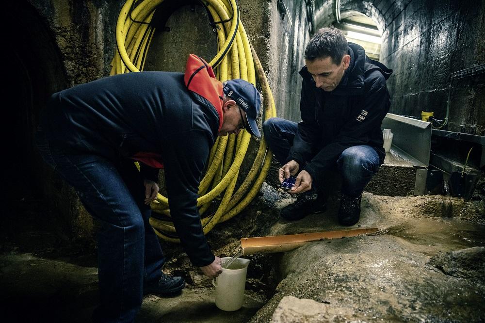 Mesure manuelle : Hans Züger, le gardien du barrage, et Ralph Kienle mesurent la quantité totale d’eau d’infiltration afin de contrôler l’appareil de mesure automatique.