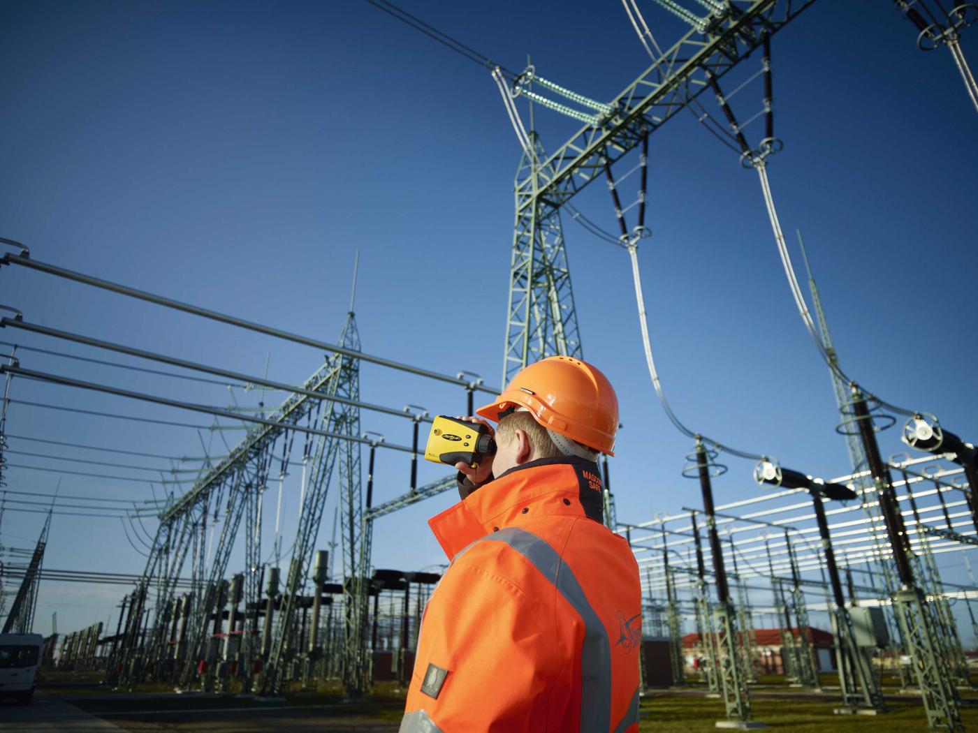 Sécurité d’approvisionnement – Un technicien contrôle les écarts néces­sai­res dans une sous-station à l’aide d’un instrument de mesure optique.