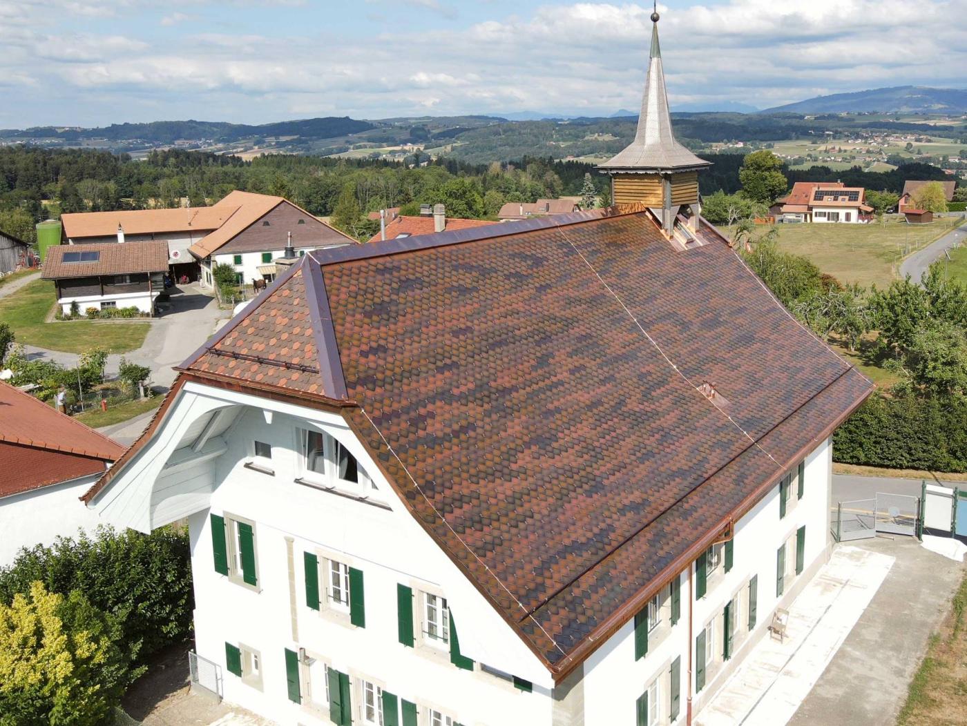 <b>Figure 1</b> Des tuiles solaires de diverses couleurs terracotta, mixées, ont été intégrées au toit de l’ancien collège de Ferlens pour obtenir un rendu esthétique reproduisant celui d’un vieux toit en terre cuite.